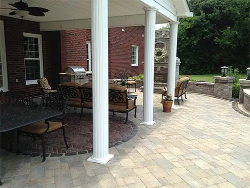 An arbor over a patio with some outdoor furniture