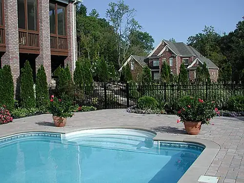 A beautiful pool deck outside of a big house